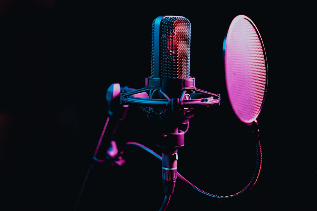 our-story Close-up image of a condenser microphone with a pop filter in a studio setting, featuring atmospheric lighting.