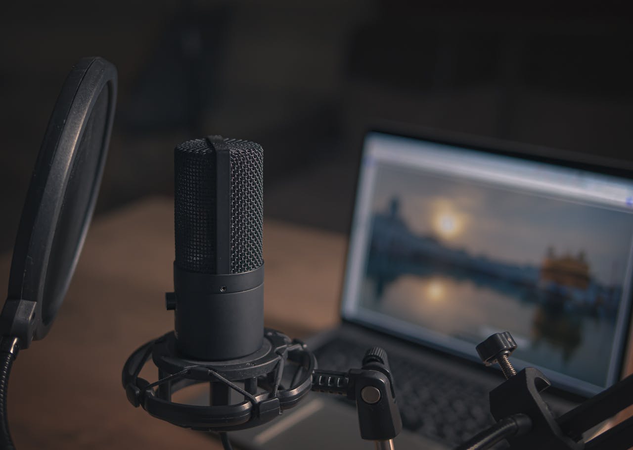 heros-img Close-up of a microphone with a pop filter and laptop, ideal for modern studio production.